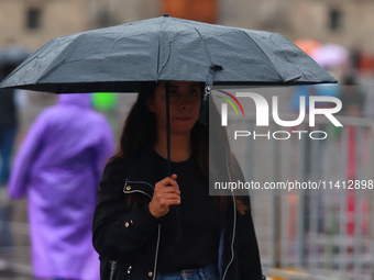 A person is covering herself from the rain with an umbrella while walking through downtown in Mexico City, Mexico, on July 10, 2024. (