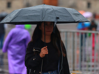 A person is covering herself from the rain with an umbrella while walking through downtown in Mexico City, Mexico, on July 10, 2024. (