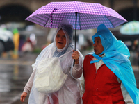 People are covering themselves from the rain with umbrellas while walking through downtown in Mexico City, Mexico, on July 10, 2024. (