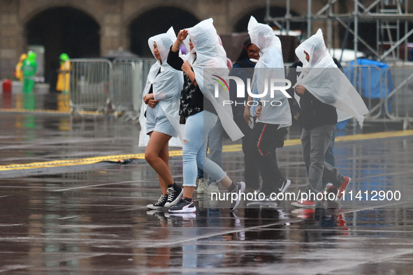 People are covering themselves from the rain with raincoats while walking through downtown in Mexico City, Mexico, on July 10, 2024. 