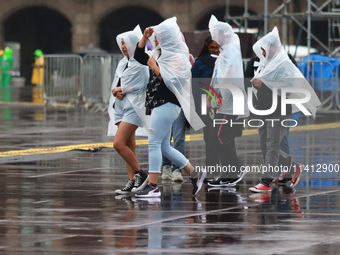 People are covering themselves from the rain with raincoats while walking through downtown in Mexico City, Mexico, on July 10, 2024. (