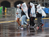 People are covering themselves from the rain with raincoats while walking through downtown in Mexico City, Mexico, on July 10, 2024. (