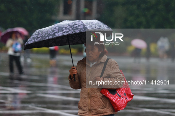 A person is covering herself from the rain with an umbrella while walking through downtown in Mexico City, Mexico, on July 10, 2024. 