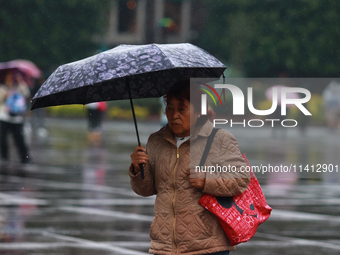 A person is covering herself from the rain with an umbrella while walking through downtown in Mexico City, Mexico, on July 10, 2024. (