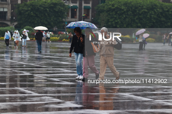 People are covering themselves from the rain with umbrellas while walking through downtown in Mexico City, Mexico, on July 10, 2024. 