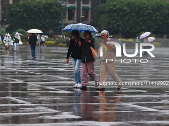 People are covering themselves from the rain with umbrellas while walking through downtown in Mexico City, Mexico, on July 10, 2024. (