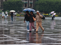 People are covering themselves from the rain with umbrellas while walking through downtown in Mexico City, Mexico, on July 10, 2024. (