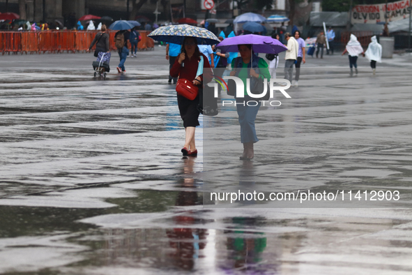 People are covering themselves from the rain with umbrellas while walking through downtown in Mexico City, Mexico, on July 10, 2024. 