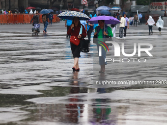 People are covering themselves from the rain with umbrellas while walking through downtown in Mexico City, Mexico, on July 10, 2024. (