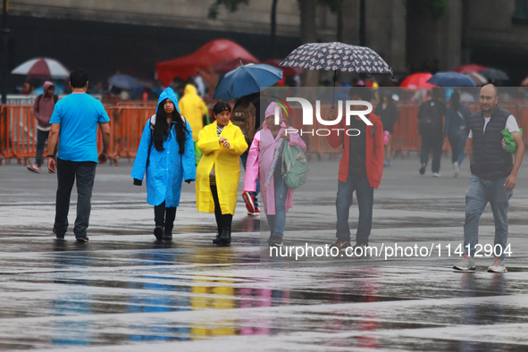 People are covering themselves from the rain with umbrellas while walking through downtown in Mexico City, Mexico, on July 10, 2024. 