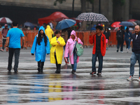 People are covering themselves from the rain with umbrellas while walking through downtown in Mexico City, Mexico, on July 10, 2024. (