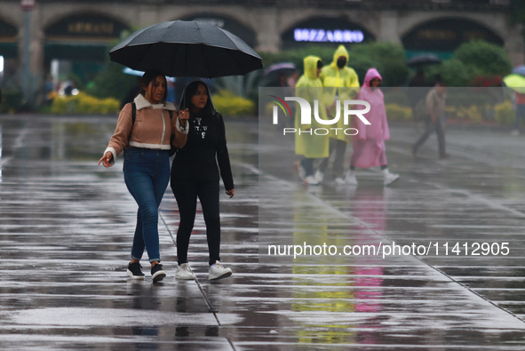 People are covering themselves from the rain with umbrellas while walking through downtown in Mexico City, Mexico, on July 10, 2024. 