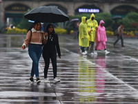 People are covering themselves from the rain with umbrellas while walking through downtown in Mexico City, Mexico, on July 10, 2024. (