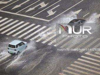 Vehicles are driving through heavy rain in the West Coast New Area of Qingdao, Shandong province, China, on July 16, 2024. (