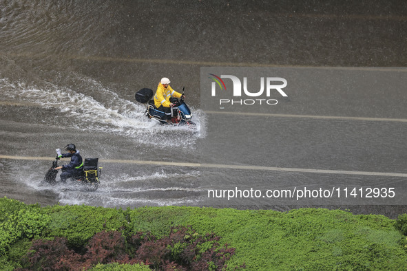 Citizens are riding during a rainstorm in the West Coast New Area of Qingdao, Shandong province, China, on July 16, 2024. 