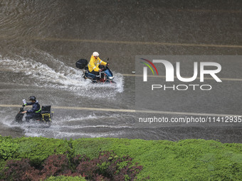 Citizens are riding during a rainstorm in the West Coast New Area of Qingdao, Shandong province, China, on July 16, 2024. (