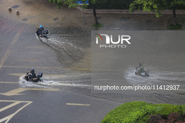 Citizens are riding during a rainstorm in the West Coast New Area of Qingdao, Shandong province, China, on July 16, 2024. 