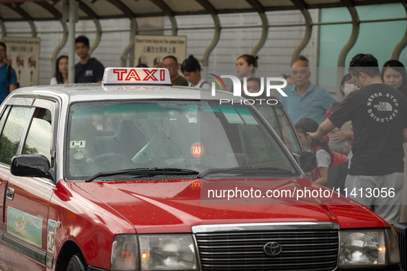 A taxi cab is stopping at a taxi stop in Hong Kong, on July 16, 2024. 