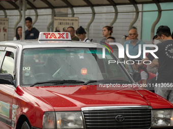 A taxi cab is stopping at a taxi stop in Hong Kong, on July 16, 2024. (