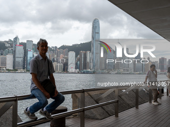 A man is sitting at the promenade in front of the Hong Kong Skyline in Hong Kong, on July 16, 2024. (