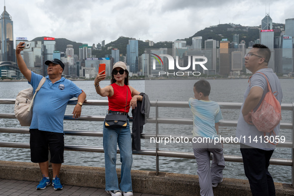 People are taking photos with the Hong Kong Skyline in Hong Kong, on July 16, 2024. 