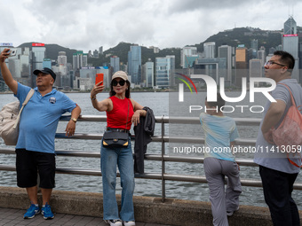 People are taking photos with the Hong Kong Skyline in Hong Kong, on July 16, 2024. (