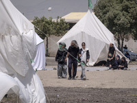 Youths are walking past the tents that are set up as symbols of the tents of Imam Hussein and his family, while participating in a religious...