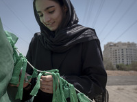 A young woman is tying a prayer symbol on a tent that is set up as a symbol of the tent of Imam Hussein during a religious festival to comme...