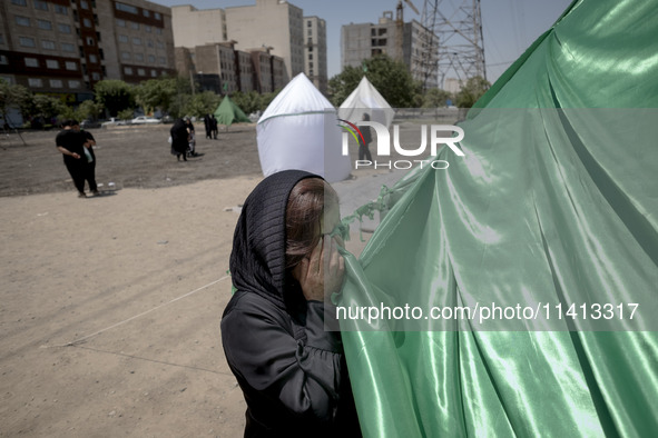 An Afghan refugee woman is praying while standing next to a tent that is set up as a symbol of the tent of Imam Hussein during a religious f...