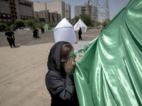 An Afghan refugee woman is praying while standing next to a tent that is set up as a symbol of the tent of Imam Hussein during a religious f...