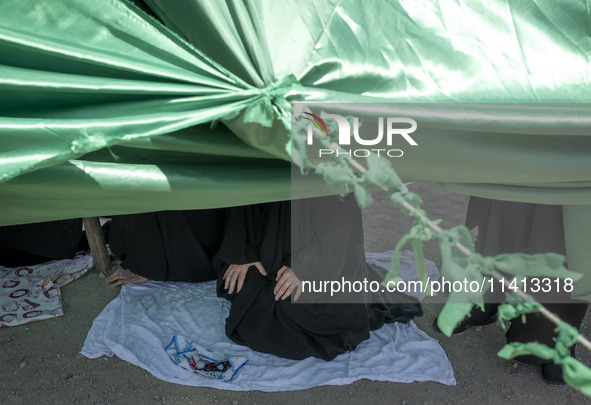 An Iraqi woman living in Iran is praying while sitting at a tent that is set up as a symbol of the tent of Imam Hussein during a religious f...