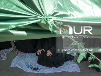 An Iraqi woman living in Iran is praying while sitting at a tent that is set up as a symbol of the tent of Imam Hussein during a religious f...