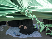 An Iraqi woman living in Iran is praying while sitting at a tent that is set up as a symbol of the tent of Imam Hussein during a religious f...