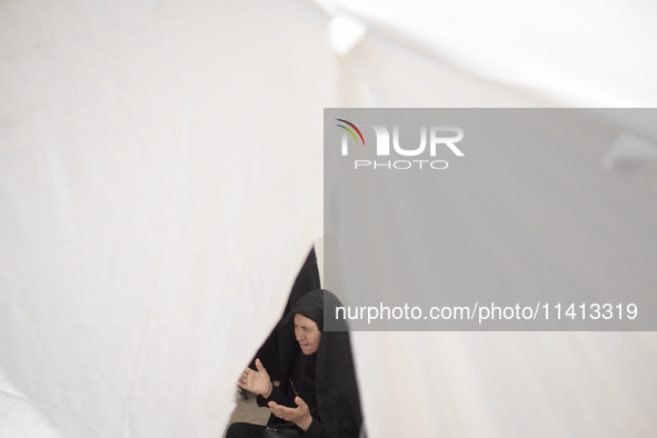 An Iraqi woman living in Iran is praying while sitting at a tent that is set up as a symbol of the tent of Imam Hussein during a religious f...