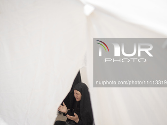 An Iraqi woman living in Iran is praying while sitting at a tent that is set up as a symbol of the tent of Imam Hussein during a religious f...