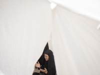 An Iraqi woman living in Iran is praying while sitting at a tent that is set up as a symbol of the tent of Imam Hussein during a religious f...