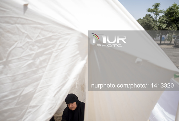 An Iraqi woman living in Iran is praying while sitting at a tent that is set up as a symbol of the tent of Imam Hussein during a religious f...