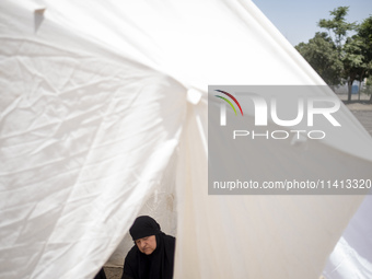 An Iraqi woman living in Iran is praying while sitting at a tent that is set up as a symbol of the tent of Imam Hussein during a religious f...