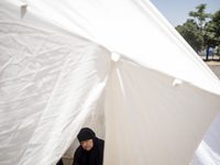 An Iraqi woman living in Iran is praying while sitting at a tent that is set up as a symbol of the tent of Imam Hussein during a religious f...