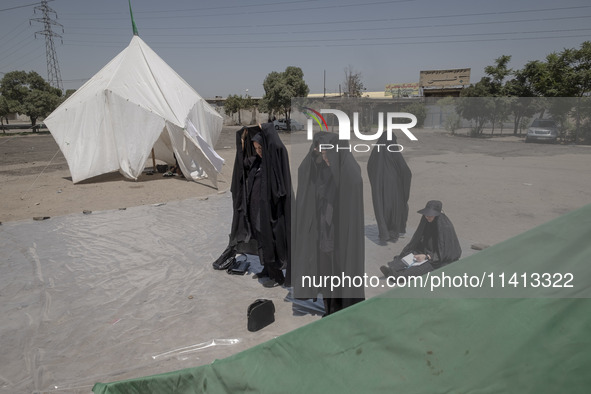 Veiled women are praying next to the tents that are set up in an area, serving as the symbol of the tents of Imam Hussein, during a religiou...