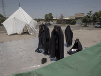 Veiled women are praying next to the tents that are set up in an area, serving as the symbol of the tents of Imam Hussein, during a religiou...