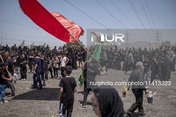 A young Iraqi boy living in Iran is waving a giant religious flag while participating in a religious festival to commemorate Ashura in the D...