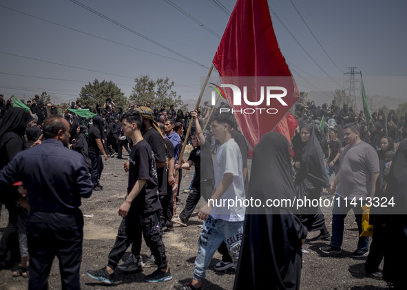 A young Iraqi boy living in Iran is waving a giant religious flag while participating in a religious festival to commemorate Ashura in the D...