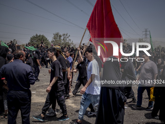 A young Iraqi boy living in Iran is waving a giant religious flag while participating in a religious festival to commemorate Ashura in the D...