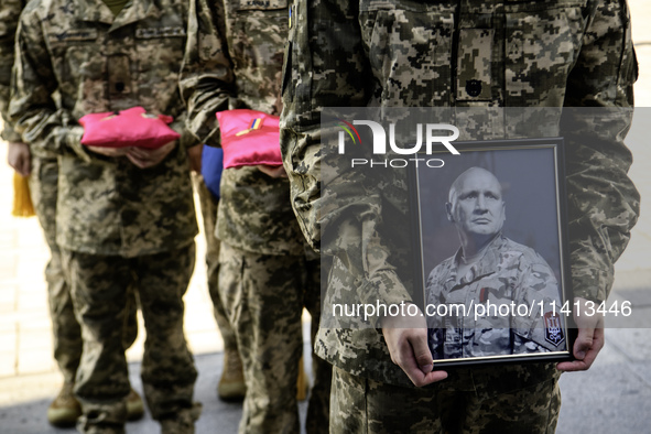 A serviceman is holding a portrait of Mykola Kokhanivskyi, commander of the OUN (Organisation of Ukrainian Nationalists) volunteer battalion...