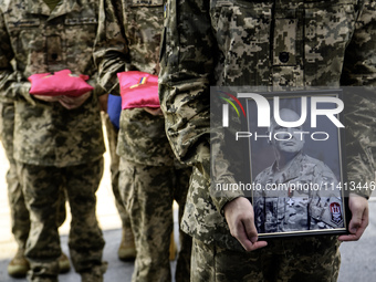 A serviceman is holding a portrait of Mykola Kokhanivskyi, commander of the OUN (Organisation of Ukrainian Nationalists) volunteer battalion...