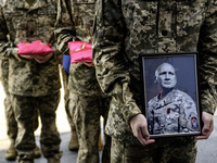 A serviceman is holding a portrait of Mykola Kokhanivskyi, commander of the OUN (Organisation of Ukrainian Nationalists) volunteer battalion...