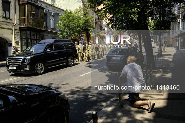 A man is kneeling as the funeral procession for Mykola Kokhanivskyi, commander of the OUN (Organisation of Ukrainian Nationalists) volunteer...