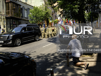 A man is kneeling as the funeral procession for Mykola Kokhanivskyi, commander of the OUN (Organisation of Ukrainian Nationalists) volunteer...