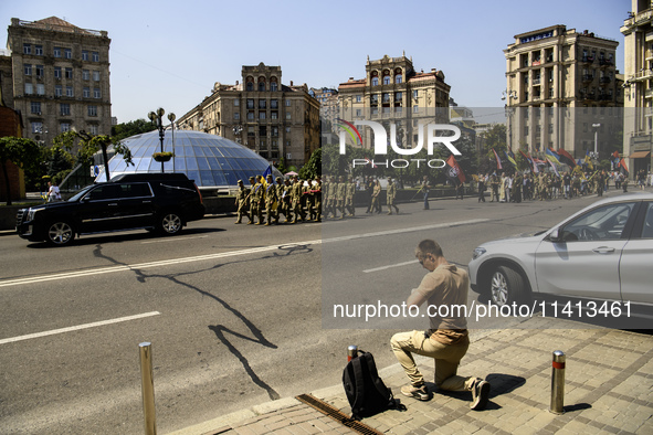 A man is kneeling as the funeral procession for Mykola Kokhanivskyi, commander of the OUN (Organisation of Ukrainian Nationalists) volunteer...